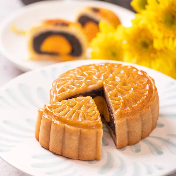 Festival de Medio Otoño concepto de comida tradicional - Hermosa torta de luna cortada en placa de patrón azul sobre fondo blanco con flor, primer plano, espacio de copia — Foto de Stock