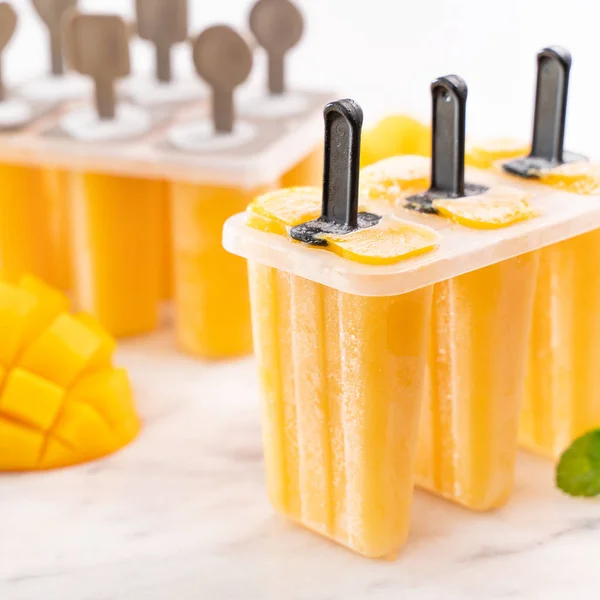 Friss mangó gyümölcs Popsicle jég a műanyag alakításában dobozban fényes márvány asztalra. Nyári hangulat koncepció terméktervezés, közelről. — Stock Fotó