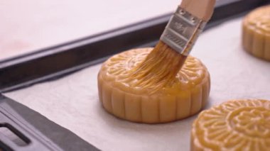 Orta Sonbahar Festivali için ay kek yapma Süreci - Kadın pişirme den önce pasta yüzeyinde yumurta sıvı fırçalama. Şenlikli ev yapımı konsept, yakın çekim.