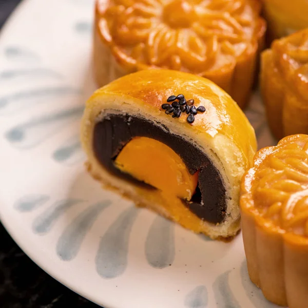 Tasty baked egg yolk pastry moon cake for Mid-Autumn Festival on black slate dark background. Chinese festive food concept, close up, copy space.