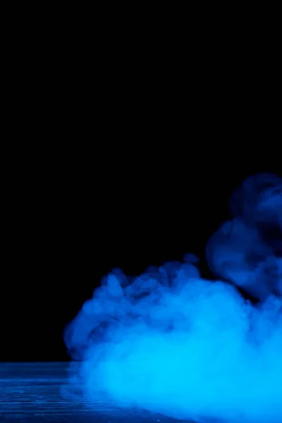 Immagine concettuale di fumo blu isolato su sfondo nero scuro e tavolo in legno . — Foto Stock