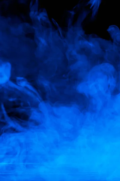 Image conceptuelle de fumée bleue isolée sur fond noir foncé et table en bois . — Photo