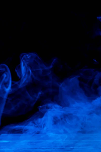 Imagen conceptual de humo azul aislado sobre fondo negro oscuro y mesa de madera . —  Fotos de Stock