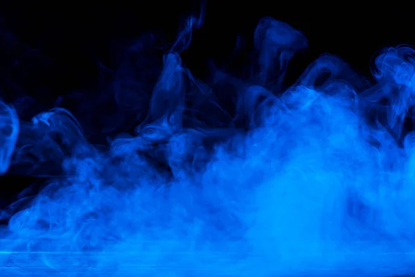 Immagine concettuale di fumo blu isolato su sfondo nero scuro e tavolo in legno . — Foto Stock