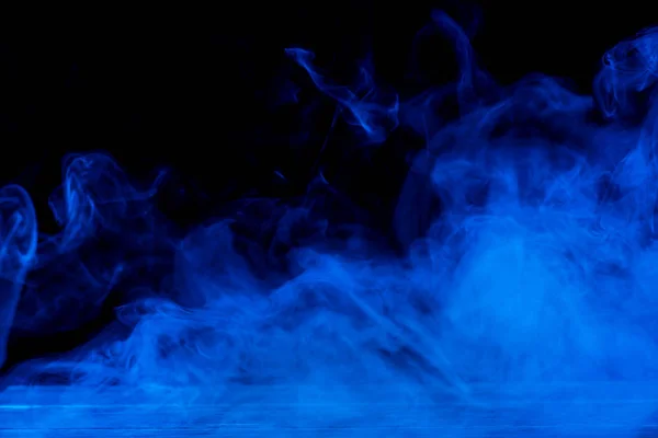 Immagine concettuale di fumo blu isolato su sfondo nero scuro e tavolo in legno . — Foto Stock