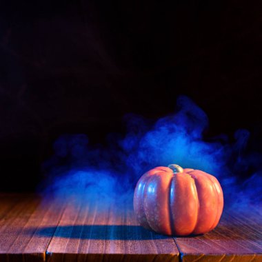 Halloween concept - Orange pumpkin lantern on a dark wooden table with double colored smoke around the background, trick or treat, close up. clipart