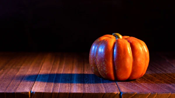 Halloween-Konzept - orangefarbene Kürbislaterne auf dunklem Holztisch mit schwarzem Hintergrund, Trick oder Leckerbissen, Nahaufnahme. — Stockfoto