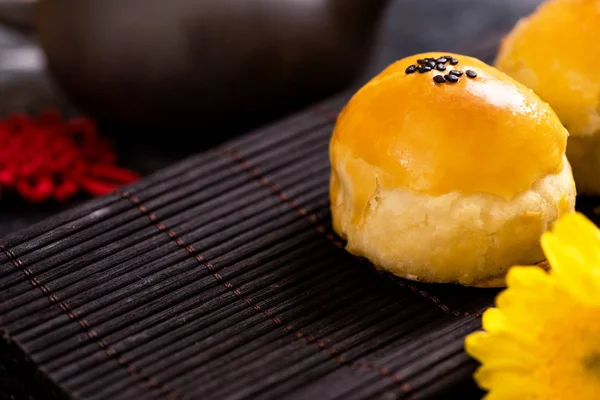 Tasty baked egg yolk pastry moon cake for Mid-Autumn Festival on black slate dark background. Chinese festive food concept, close up, copy space.