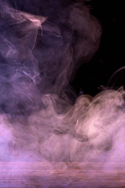 Immagine concettuale di fumo multicolore isolato su sfondo nero scuro e tavolo in legno. — Foto Stock