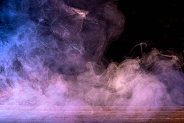 Immagine concettuale di fumo multicolore isolato su sfondo nero scuro e tavolo in legno. — Foto Stock