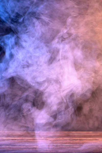Imagen conceptual de humo multicolor aislado sobre fondo negro oscuro y mesa de madera . —  Fotos de Stock