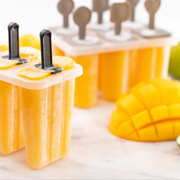 Eis am Stiel aus frischen Mangofrüchten in der Plastikbox auf einem hellen Marmortisch. Sommerstimmung Konzept Produktdesign, hautnah. — Stockfoto