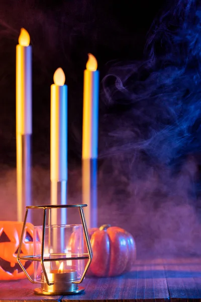 Concetto di Halloween, lanterna di zucca arancione e candele su un tavolo di legno scuro con fumo verde-arancio intorno allo sfondo, dolcetto o scherzetto, primo piano — Foto Stock