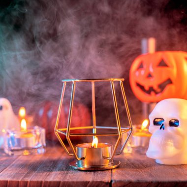 Cadılar Bayramı konsepti, turuncu kabak fener ve arka plan etrafında yeşil-turuncu duman ile koyu ahşap bir masa üzerinde mumlar, hile veya tedavi, yakın