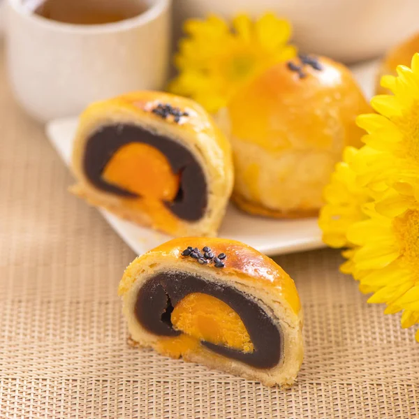 Tasty baked egg yolk pastry moon cake for Mid-Autumn Festival on bright wooden table background. Chinese festive food concept, close up, copy space.