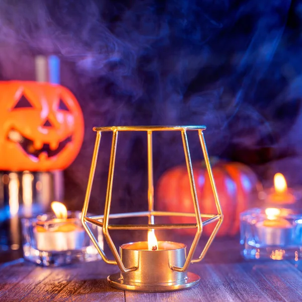 Cadılar Bayramı konsepti, turuncu kabak fener ve arka plan etrafında yeşil-turuncu duman ile koyu ahşap bir masa üzerinde mumlar, hile veya tedavi, yakın