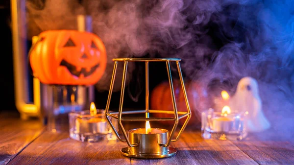 Cadılar Bayramı konsepti, turuncu kabak fener ve arka plan etrafında yeşil-turuncu duman ile koyu ahşap bir masa üzerinde mumlar, hile veya tedavi, yakın