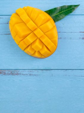 Taze mango - parlak mavi ahşap arka plan üzerinde yeşil yaprakları ile güzel doğranmış meyve. Tropikal meyve tasarım konsepti. Düz yatıyordu. Üst te. Kopyalama alanı