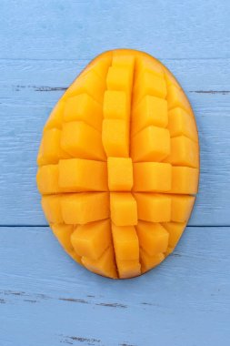 Taze mango - parlak mavi ahşap arka plan üzerinde yeşil yaprakları ile güzel doğranmış meyve. Tropikal meyve tasarım konsepti. Düz yatıyordu. Üst te. Kopyalama alanı