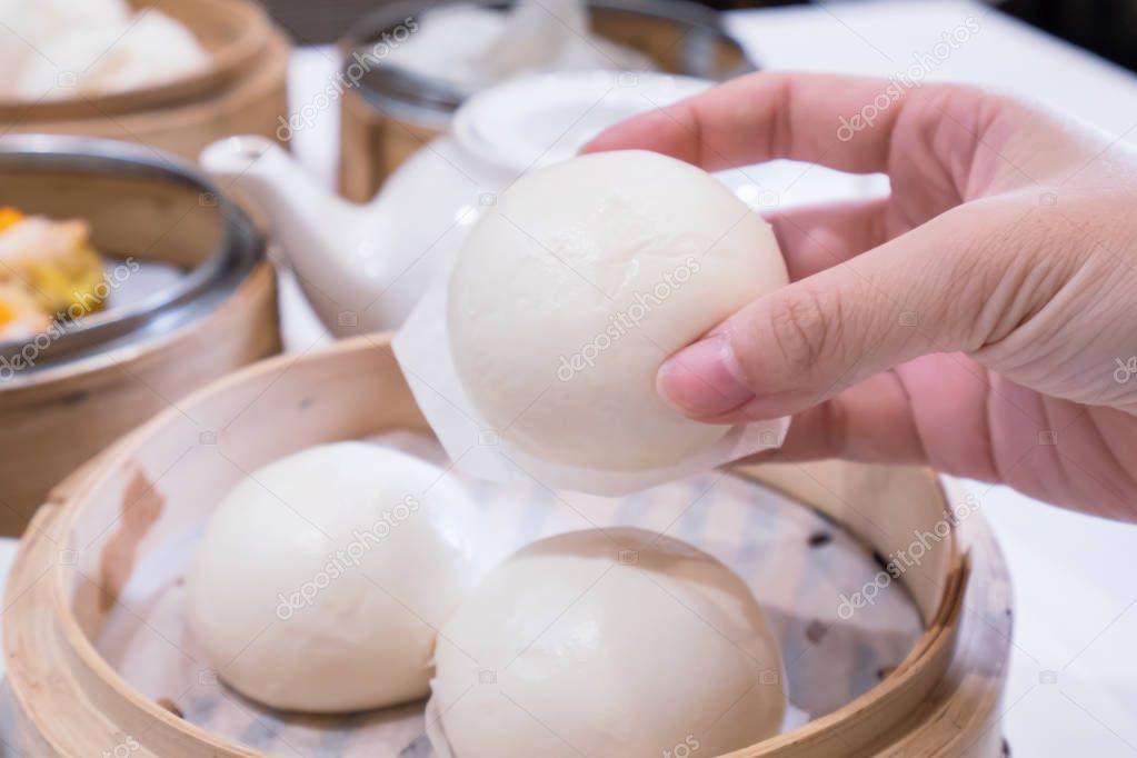 Delicious dim sum, famous cantonese food in asia, fresh and hot salted creamy custard buns in bamboo steamer in hong kong yumcha restaurant, close up