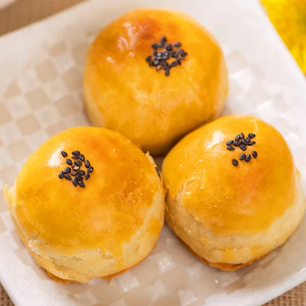 Tasty baked egg yolk pastry moon cake for Mid-Autumn Festival on bright wooden table background. Chinese festive food concept, close up, copy space.