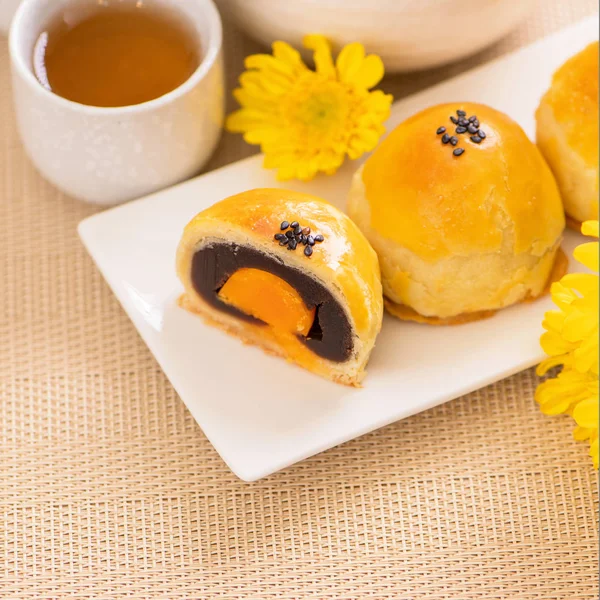 Tasty baked egg yolk pastry moon cake for Mid-Autumn Festival on bright wooden table background. Chinese festive food concept, close up, copy space.
