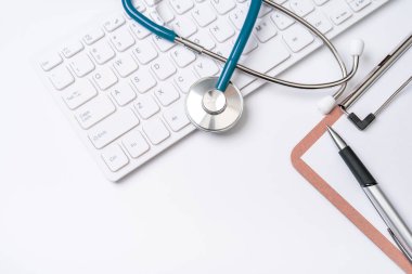Doktor kavramı teşhis - tıbbi kayıt durumda bilgisayar klavyesi üzerinde stetoskop ve beyaz çalışma masasında kalem. Üst görünüm, düz döşeme, kopyalama alanı