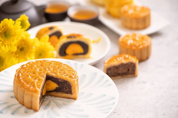 Conceito de comida tradicional do Festival do Meio do Outono - Bolo de lua cortado bonito na placa de padrão azul no fundo branco com flor, close-up, espaço de cópia — Fotografia de Stock