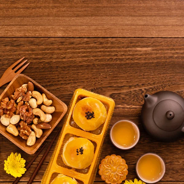 Moon cakes with tea on dark wooden table, holiday concept of Mid-Autumn festival traditional food layout design, top view, flat lay, copy space.