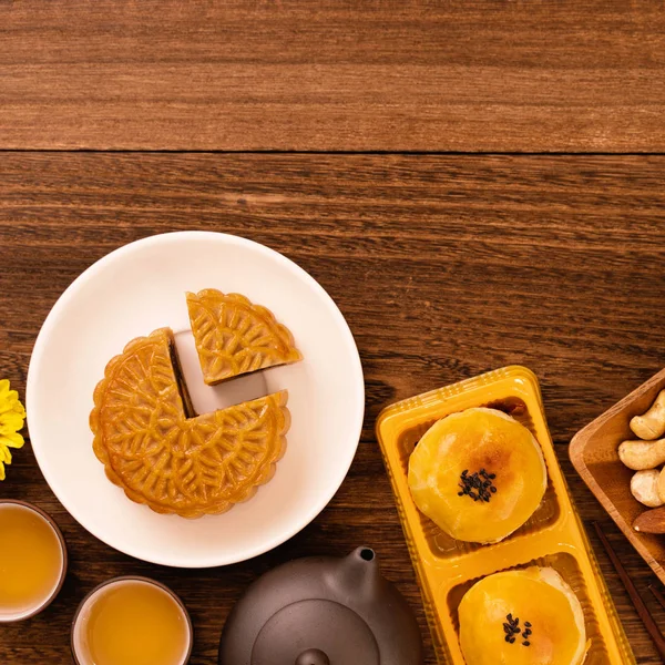 Moon cakes with tea on dark wooden table, holiday concept of Mid-Autumn festival traditional food layout design, top view, flat lay, copy space.