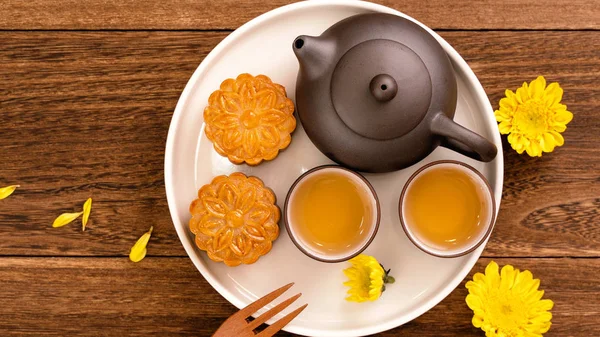 Moon cakes with tea on dark wooden table, holiday concept of Mid-Autumn festival traditional food layout design, top view, flat lay, copy space.