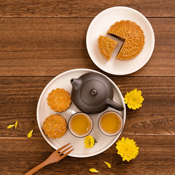 Moon cakes with tea on dark wooden table, holiday concept of Mid-Autumn festival traditional food layout design, top view, flat lay, copy space.