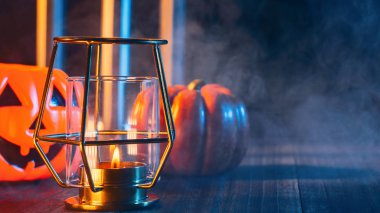 Cadılar Bayramı konsepti, mum ve mumluk kadar aydınlatma ile ürkütücü süslemeleri koyu ahşap bir masa etrafında mavi sesi duman, yakın.