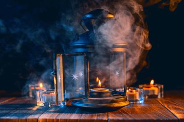 Cadılar Bayramı konsepti, mum ve mumluk kadar aydınlatma ile ürkütücü süslemeleri koyu ahşap bir masa etrafında mavi sesi duman, yakın.
