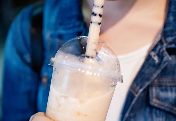Giovane ragazza in giacca di denim sta bevendo zucchero di canna aromatizzato tapioca perla bolla tè al latte con paglia di vetro nel mercato notturno di Taiwan, da vicino, bokeh — Foto Stock