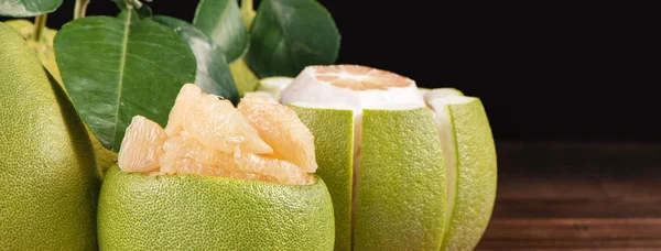 Fresh peeled pomelo, grapefruit, shaddock with green leaves on dark wooden plank table. Seasonal fruit near mid-autumn festival, close up, copy space — Stock Photo, Image