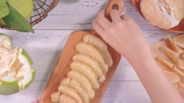 Genç asyalı kadın hazırlanıyor ve parlak beyaz ahşap masa üzerinde mutfakta bir tepsi üzerinde soyulmuş taze pomelo hizmet, üst görünüm, havai görünüm, yaşam tarzı.