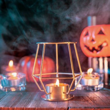 Cadılar Bayramı konsepti, mum ve mumluk kadar aydınlatma ile ürkütücü süslemeleri koyu ahşap bir masa etrafında yeşil tonu duman ile, yakın.