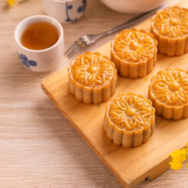 Moon cakes with tea on bright wooden table and serving try, holiday concept of Mid-Autumn festival traditional food layout design, close up, copy space. — Stock Photo, Image