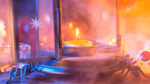 Halloween-Konzept, gruselige Dekoration mit brennender Kerze und Kerzenständer mit blauem Rauch auf dunklem Holztisch, Nahaufnahme. — Stockfoto