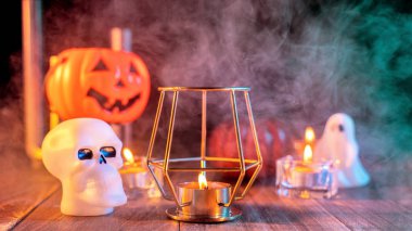 Cadılar Bayramı konsepti, mum ve mumluk kadar aydınlatma ile ürkütücü süslemeleri koyu ahşap bir masa etrafında yeşil tonu duman ile, yakın.