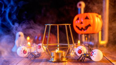 Kabak Cadılar Bayramı tatil konsept tasarımı, mum, koyu ahşap bir masa etrafında mavi tonlu duman ile ürkütücü süslemeleri, çekim yakın.