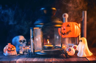 Kabak Cadılar Bayramı tatil konsept tasarımı, mum, koyu ahşap bir masa etrafında mavi tonlu duman ile ürkütücü süslemeleri, çekim yakın.
