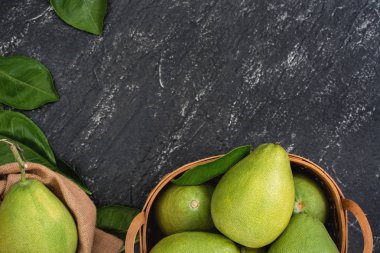 Taze pomelo, koyu siyah kayrak arka plan üzerinde yeşil yaprak ile bambu sepeti greyfurt. Sonbahar Ortası Festivali için mevsim meyveleri. Üst te. Düz yatıyordu.