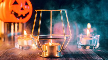 Kabak Cadılar Bayramı tatil konsept tasarımı, mum, koyu ahşap bir masa etrafında yeşil tonlu duman ile ürkütücü süslemeleri, çekim yakın.