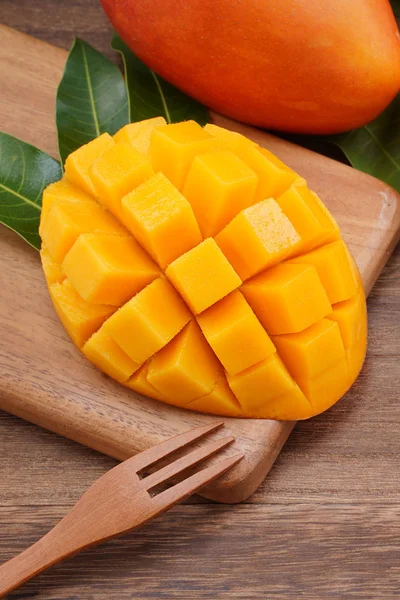 Fresh mango, beautiful chopped fruit with green leaves on dark wooden table background. Tropical fruit design concept. Flat lay. Top view. Copy space — Stock Photo, Image