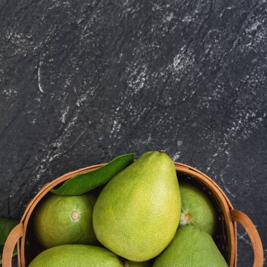 Taze pomelo, koyu siyah kayrak arka plan üzerinde yeşil yaprak ile bambu sepeti greyfurt. Sonbahar Ortası Festivali için mevsim meyveleri. Üst te. Düz yatıyordu.