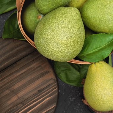 Taze pomelo, koyu siyah kayrak arka plan üzerinde yeşil yaprak ile bambu sepeti greyfurt. Sonbahar Ortası Festivali için mevsim meyveleri. Üst te. Düz yatıyordu.
