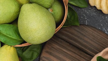 Taze pomelo, koyu siyah kayrak arka plan üzerinde yeşil yaprak ile bambu sepeti greyfurt. Sonbahar Ortası Festivali için mevsim meyveleri. Üst te. Düz yatıyordu.