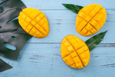 Taze mango, koyu ahşap masa arka plan üzerinde yeşil yaprakları ile güzel doğranmış meyve. Tropikal meyve tasarım konsepti. Düz yatıyordu. Üst te. Kopyalama alanı